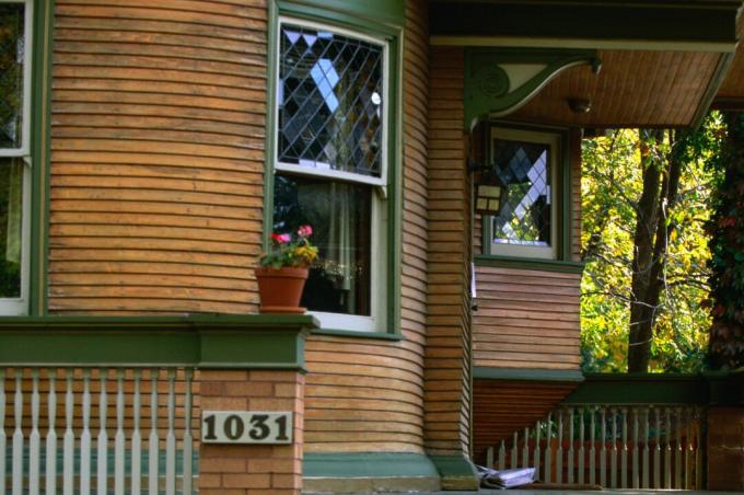 गोल घर के बरामदे का विस्तार, हरे रंग की ट्रिम के साथ प्राकृतिक लकड़ी की साइडिंग, डबल लटका हुआ खिड़कियां, सजावटी कॉर्बल्स