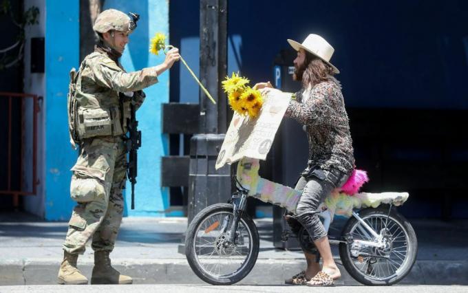 3 जून, 2020 को हॉलीवुड में जॉर्ज फ्लॉयड की मृत्यु के शांतिपूर्ण प्रदर्शन के दौरान एक राष्ट्रीय रक्षक सैनिक को एक प्रदर्शनकारी से एक फूल मिलता है।