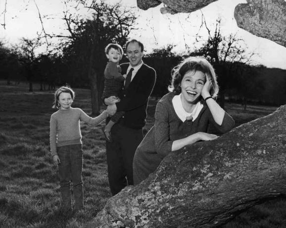 अपने बच्चों को पकड़े हुए रोनाल्ड डाहल की ब्लैक एंड व्हाइट तस्वीर; उसकी पत्नी पेट्रीसिया नील एक पेड़ पर लेट गई