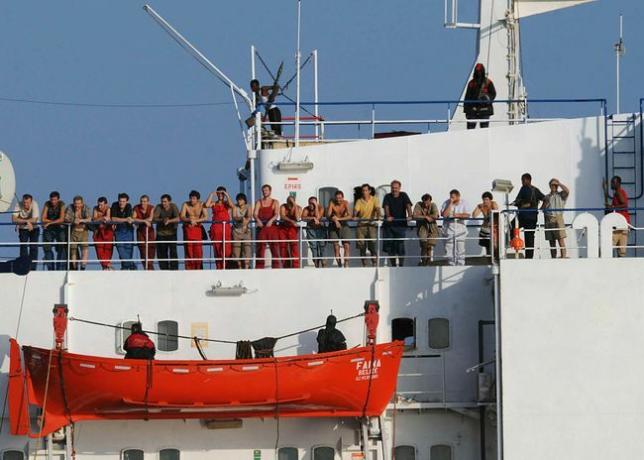 व्यापारी पोत, एमवी फेना को पकड़े हुए सोमाली समुद्री डाकू, 19 अक्टूबर, 2008 को चालक दल के सदस्यों के साथ जहाज के डेक पर खड़े हैं।
