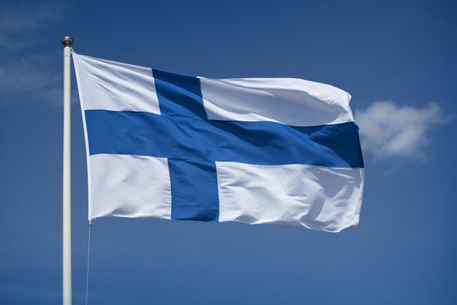 नीले आकाश की पृष्ठभूमि के साथ फ़िनिश झंडा फहराया